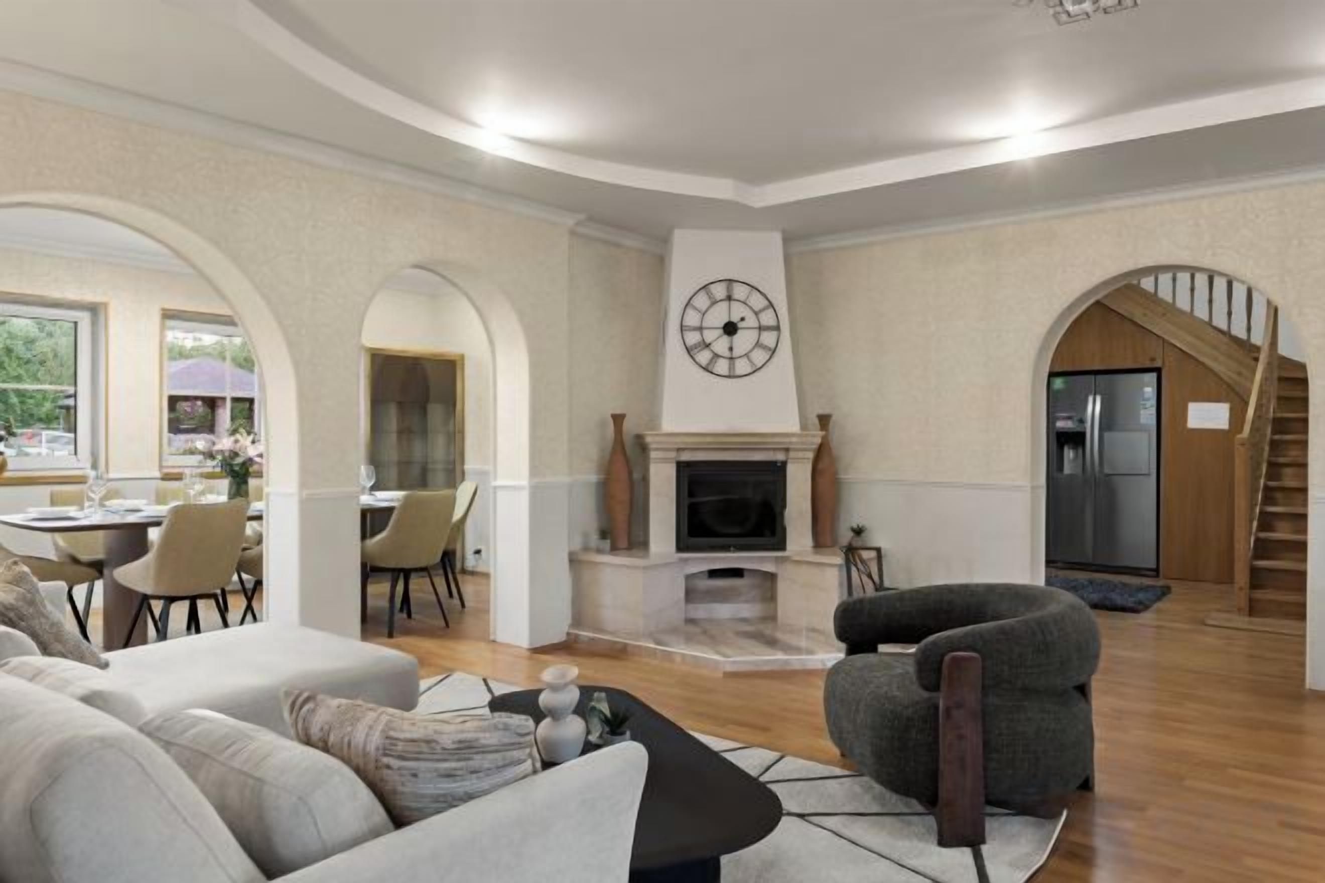 A living room with a fireplace, a dining area, and a staircase.