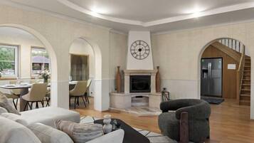 A living room with a fireplace, a dining area, and a staircase.