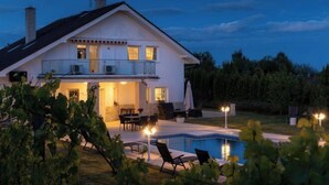 Une maison à deux étages dotée d’une piscine, d’un espace extérieur aménagé pour s’asseoir et d’un patio bien éclairé.