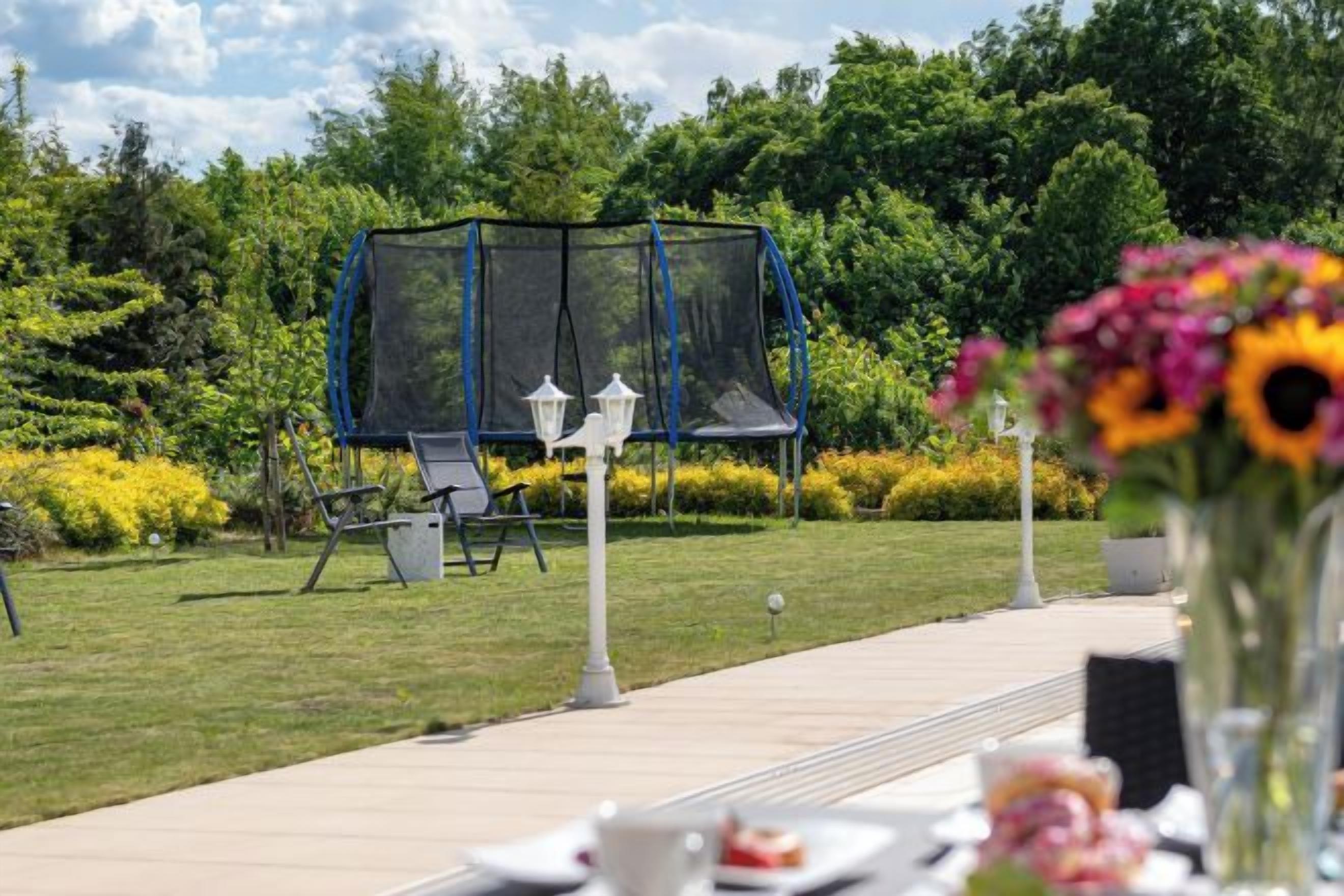 A garden with a swing set, outdoor seating, and a pathway leading to a table with a vase of flowers.