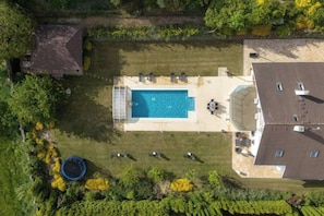 Een luchtendichtbeeld van een pand met een zwembad, een overdekt terras en een omheinde tuin.