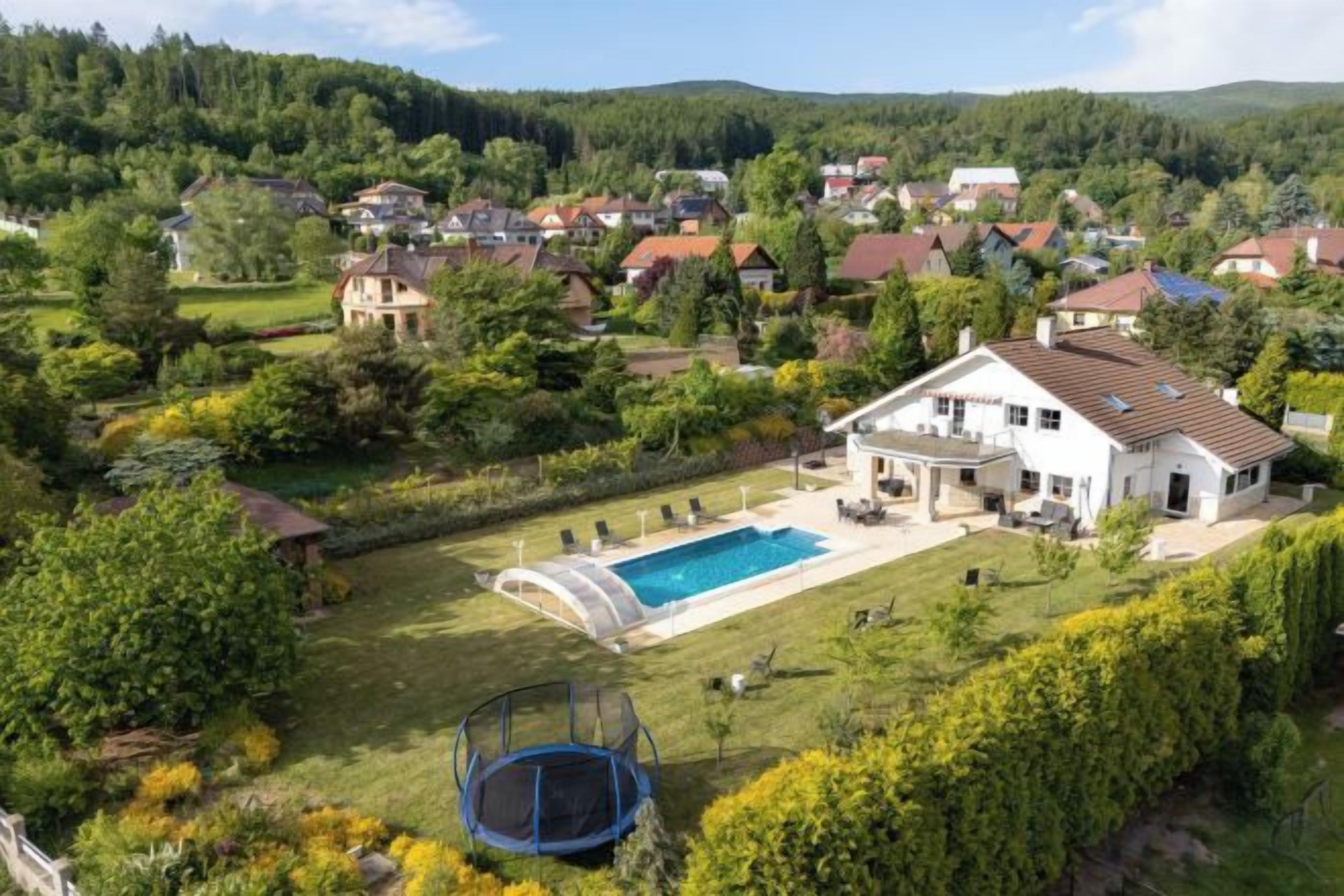 A residential property with a swimming pool, a trampoline, and a well-maintained garden.