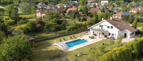 Una propiedad residencial con piscina, trampolín y un jardín bien cuidado.