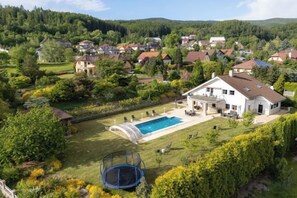 Une propriété résidentielle dotée d’une piscine, d’un trampoline et d’un jardin bien entretenu.