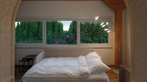 Une chambre avec une grande fenêtre, un lit et un bureau.