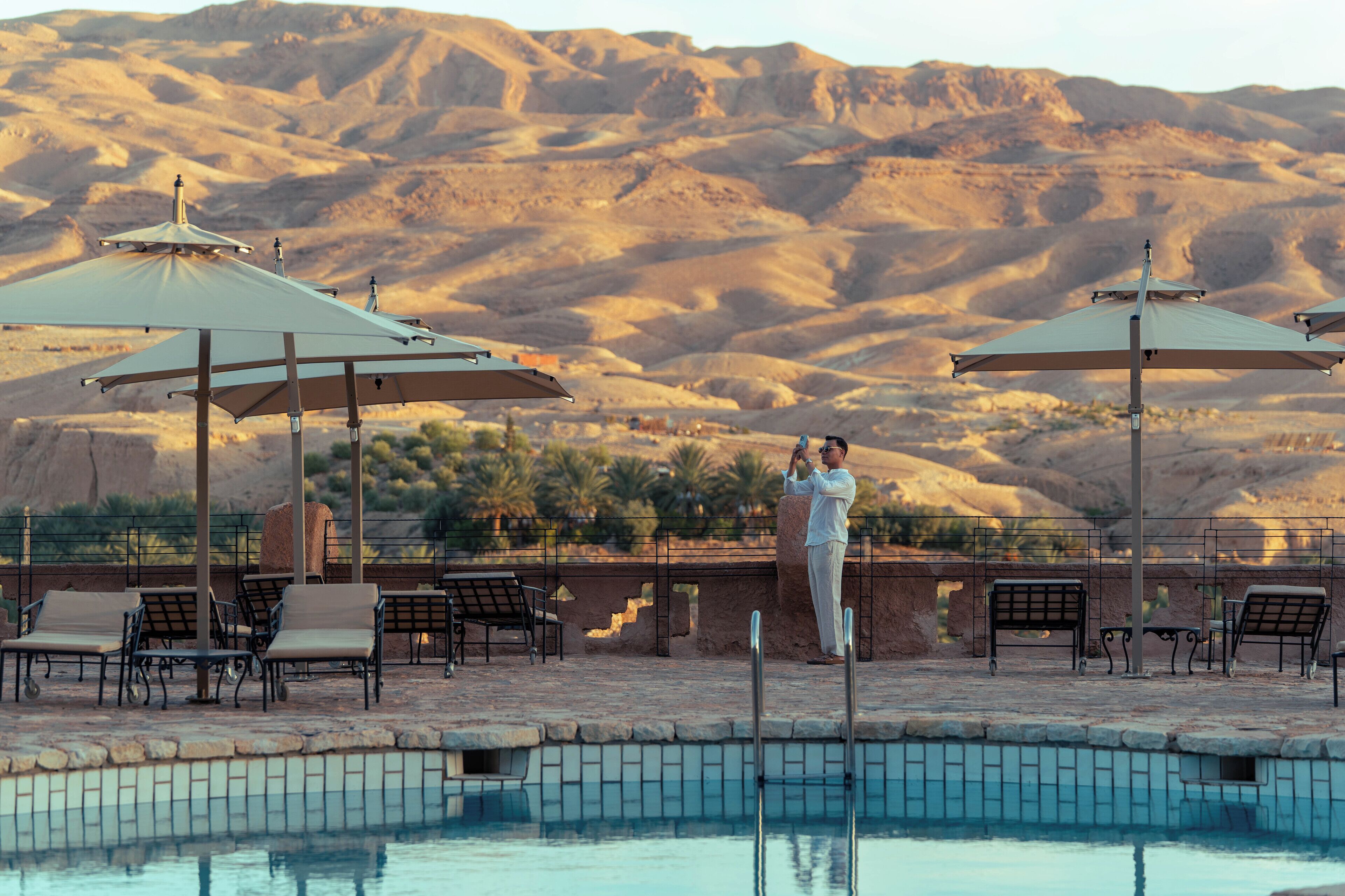 A poolside area with lounge chairs, umbrellas, and a pool.