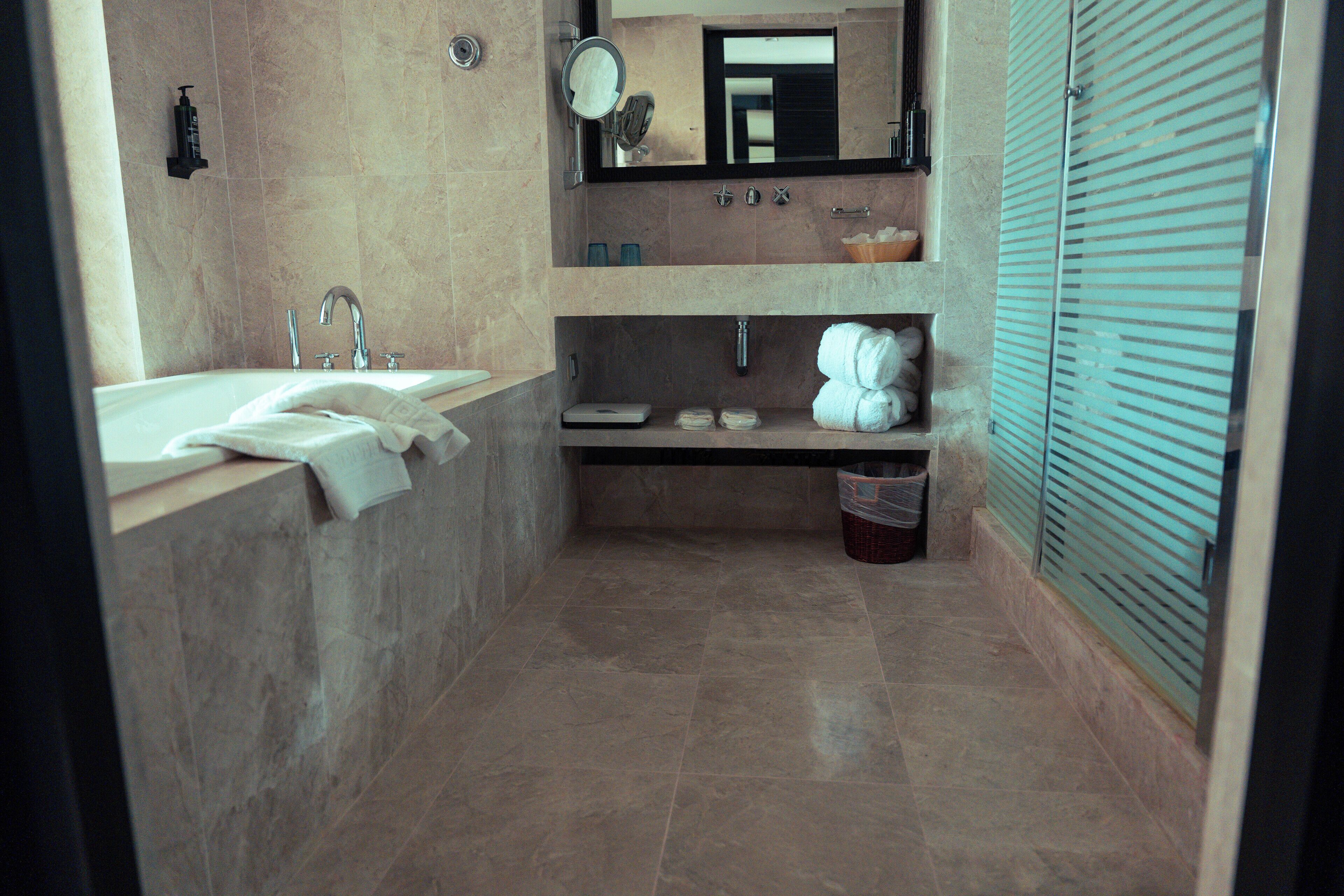 A modern bathroom with a large sink, mirror, and towel rack.