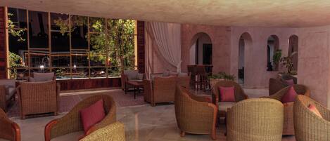 A spacious lounge area with wicker furniture and a view of the outdoors.