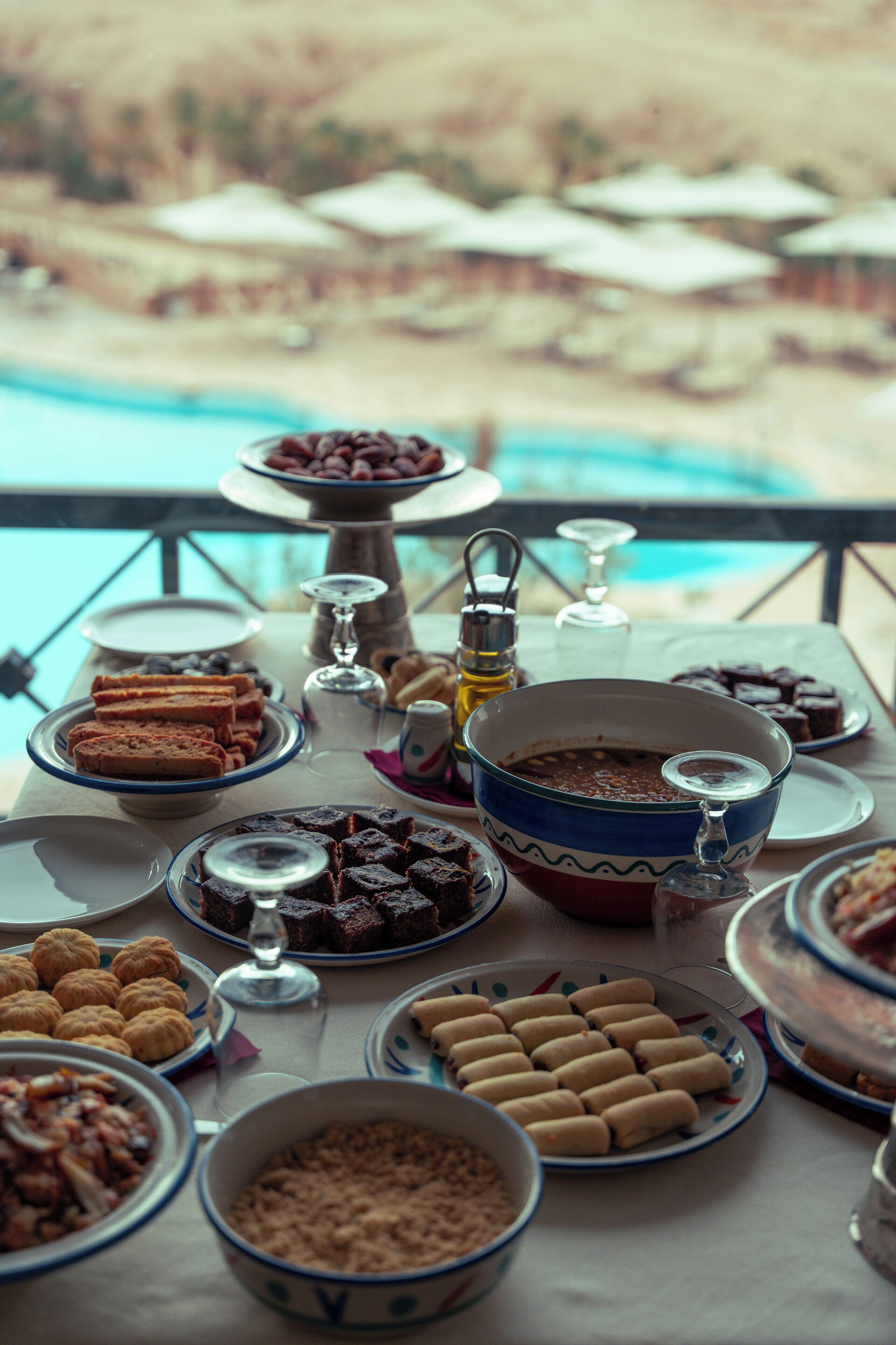 A buffet table with various dishes and a view of a pool in the background.