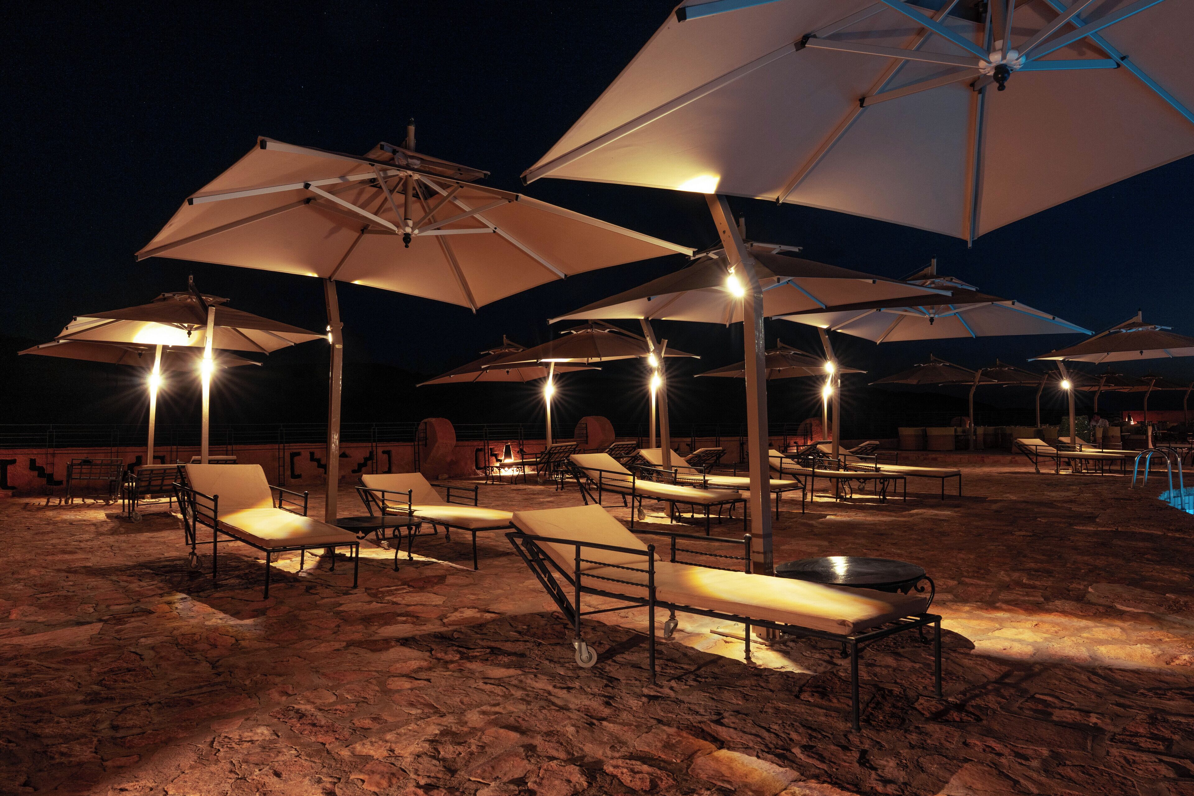 Een buiten zitgedeelte 's nachts met lounge stoelen en parasols.