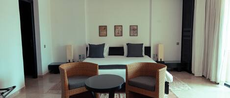 Ein Hotelzimmer mit einem Bett, zwei Stühlen, einem kleinen Tisch und einem Fenster mit Vorhängen.