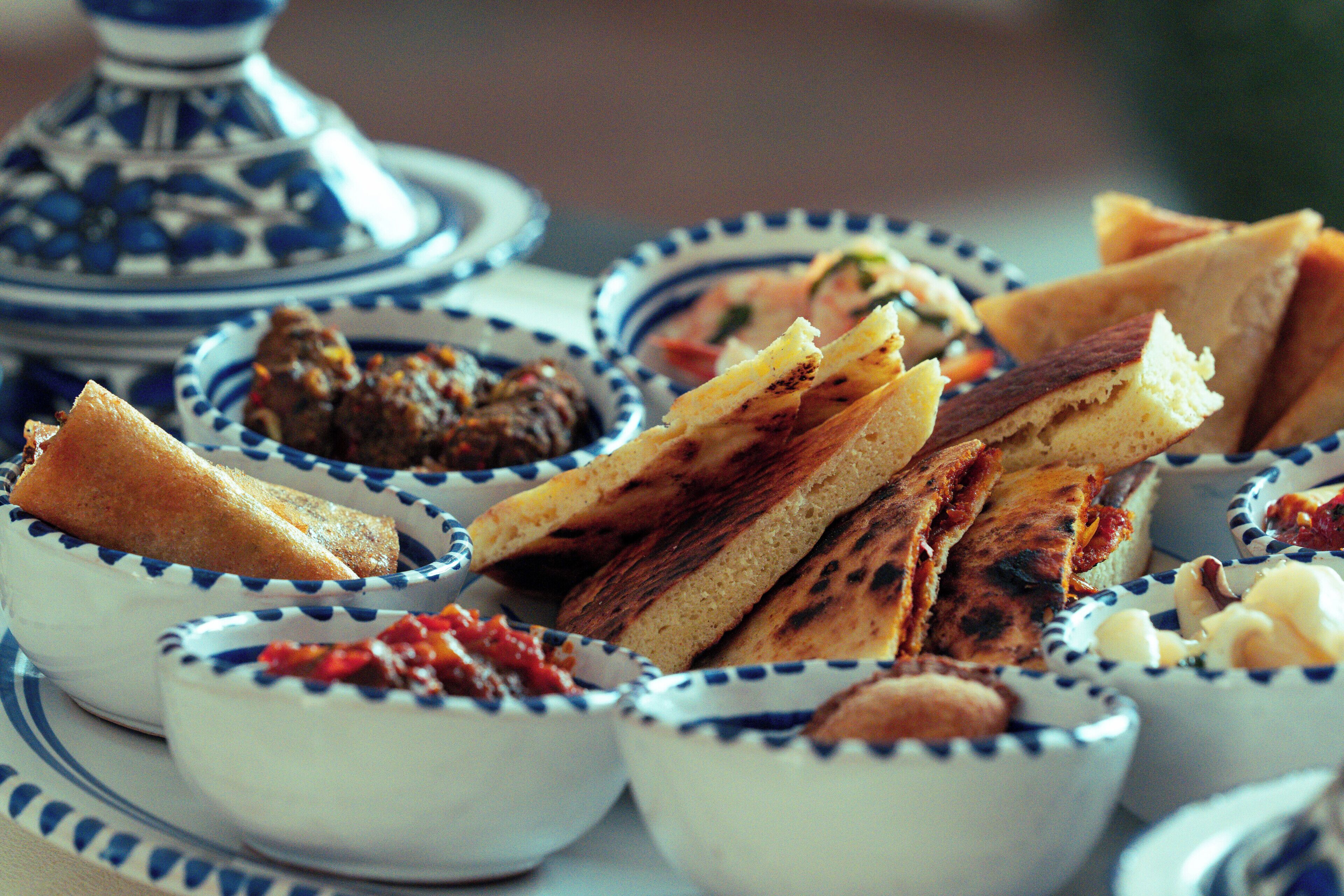 Een tafel met diverse soorten eten en kommen, waaronder brood en dipsauzen.