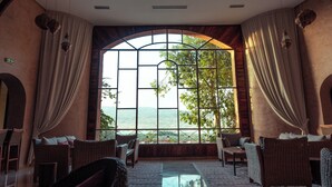 Una habitación amplia con un gran ventanal de arco que ofrece vistas panorámicas, muebles de mimbre y un diseño de techo moderno.