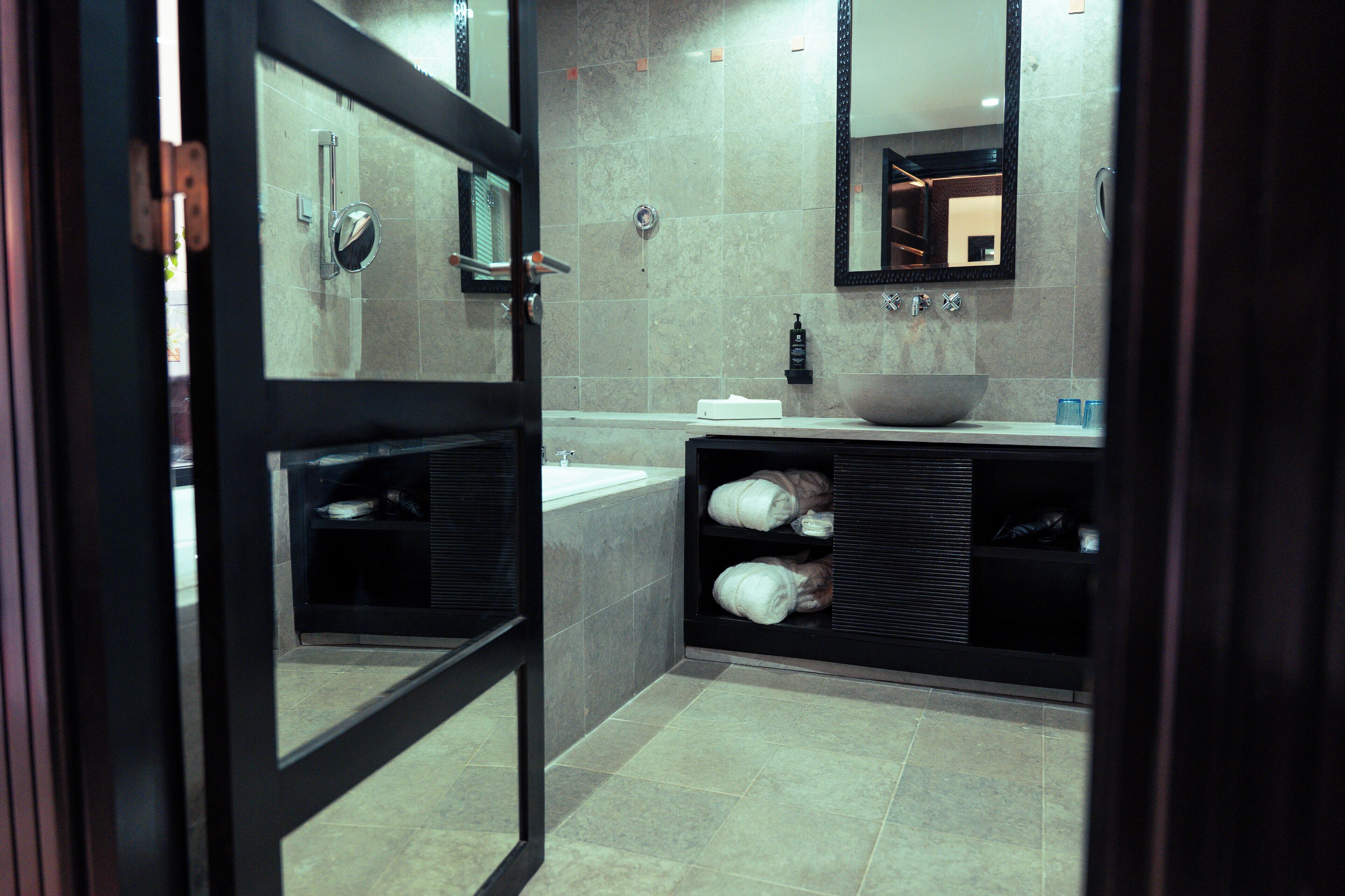 A modern bathroom with a large mirror, a sink, and a bathtub.