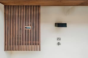 Una paret amb lamel·les verticals, un objecte rectangular petit i un objecte quadrat negre.