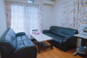 A furnished living room with a sofa, a table, and a small desk. - Toga hotel (Tokyo)