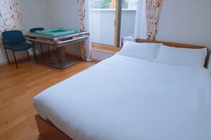A hotel room with a bed, a desk with a chair, a window with curtains, and a view of the outside. - Toga hotel (Tokyo)