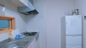 Une cuisine moderne dotée d’un évier en acier inoxydable, d’une cuisinière à gaz et d’un réfrigérateur blanc.