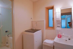 A bathroom with a shower, a toilet, a sink, and a window. - Toga hotel (Tokyo)