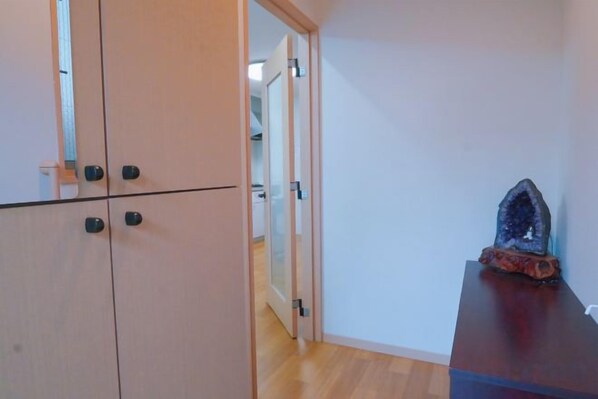 A room with a wardrobe, a wooden floor, and a table with a crystal on it.