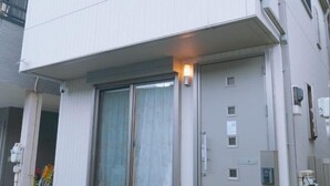 Un bâtiment moderne doté d’une grande porte d’entrée à vitres coulissantes, d’une petite fenêtre et d’un luminaire placé au-dessus de la porte.