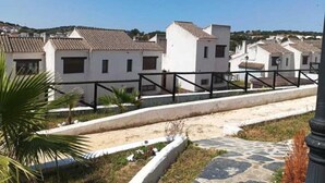Zona residencial amb edificis blancs, un camí de pedra i una tanca de metall.