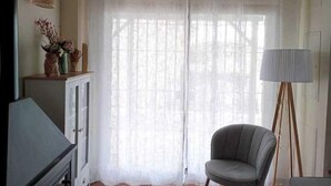 Una habitació amb un butaó gris, una làmpada i un armari amb objectes decoratius.