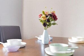 A dining table with a vase of flowers, white and light green bowls, and a spoon. - Younoyado (Osaka)
