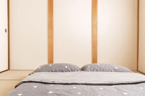 A room with a bed, a wooden wardrobe, and a plain wall.
