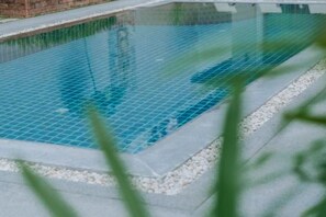 Une piscine avec un bord carrelé et un mur de briques en arrière-plan.