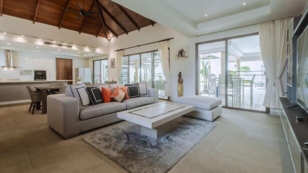 A spacious living area with a large sofa, a coffee table, and a dining area. - Luxury 4Br Villa 5 Private Pool & Jacuzzi (Phuket)