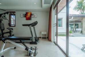 Un gimnasio con equipo de ejercicio, una cinta de correr y vistas al exterior.