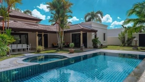 A swimming pool with a tiled edge, surrounded by a patio area with chairs and potted plants. - Luxury 4Br Villa 5 Private Pool & Jacuzzi (Phuket)