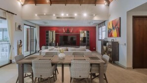 A spacious dining area with a large table and chairs, a red accent wall, a television, and a bookshelf. - Luxury 4Br Villa 5 Private Pool & Jacuzzi (Phuket)