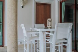 Ein Tisch und Stühle stehen an einer Wand mit einer Holztür und einem Fenster mit einem grünen Vorhang.