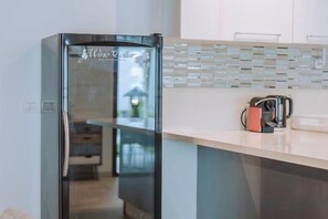 Eine moderne Küche mit einem Edelstahl-Kühlschrank, einer Arbeitsplatte mit Kaffeemaschine und einer gefliesten Rückwand.
