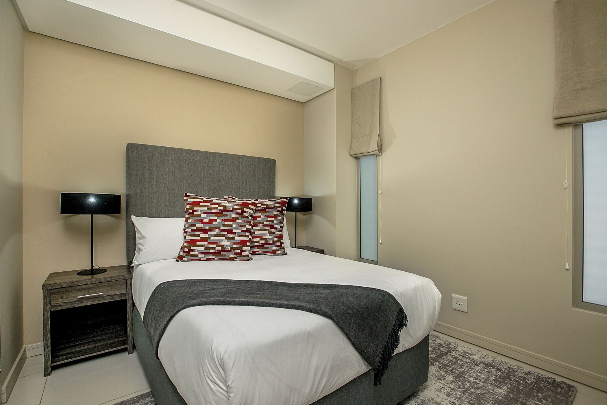 A neatly arranged bedroom with a bed, bedside tables, and a window.