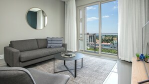 Una sala moderna con un sofá gris, una mesa de centro redonda y un ventanal con cortinas.