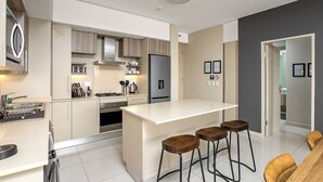 Una cocina moderna con una isla central, taburetes de bar y un comedor con mesa y sillas.