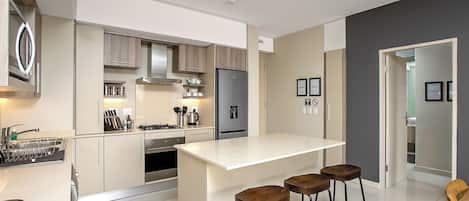 A modern kitchen with a central island, bar stools, and a dining area with a table and chairs.