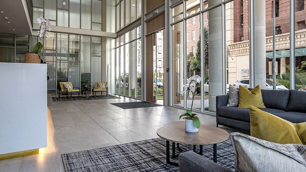 Un lobby espacioso con un diseño moderno, que incluye un sofá, una mesa de centro y un área de estar con sillones.