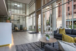 Eine großzügige Lobby im modernen Design mit einer Couch, einem Couchtisch und einer Sitzecke mit Sesseln.