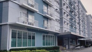 A multi-story hotel with balconies, large windows, and a covered entrance. - HapiBelles Staycation Trees Residence Tower 8 (Quezon City)