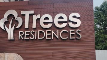 A sign for Trees Residences with a stylized tree logo and the name in capital letters.