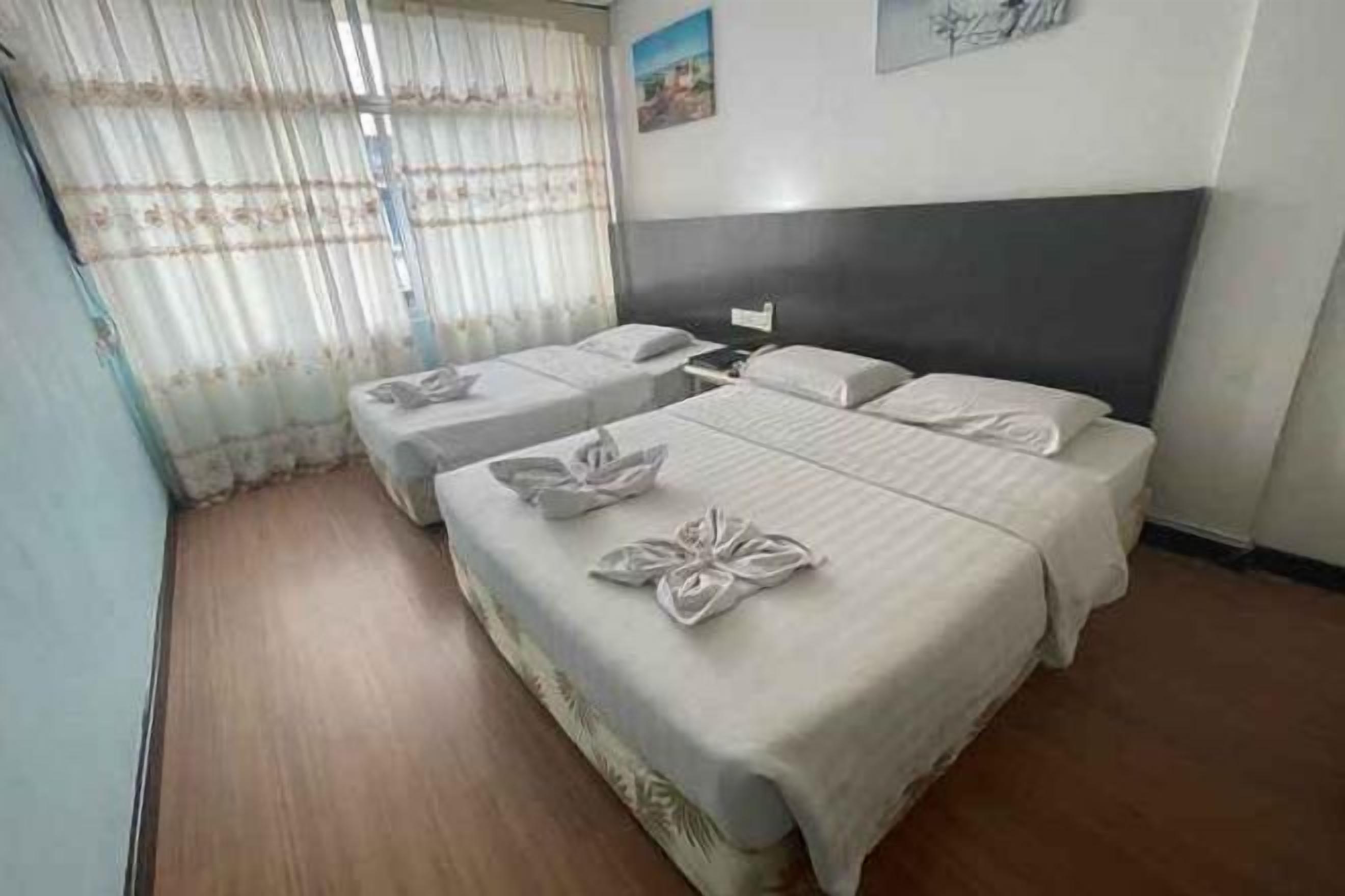 A hotel room with two beds, a nightstand, and a window with curtains.