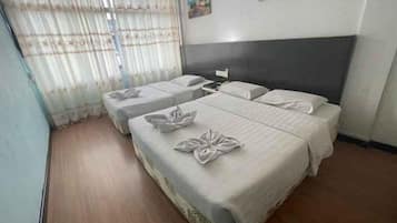 A hotel room with two beds, a nightstand, and a window with curtains.