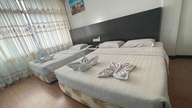 A hotel room with a large bed, two smaller beds, and a wooden floor. - Hotel Hsiang Garden (Sandakan)