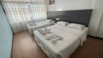 A hotel room with two beds, a nightstand, and a window with curtains.