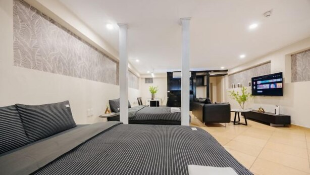 Una habitación de hotel moderna con una cama grande, un sofá, un televisor y un escritorio.