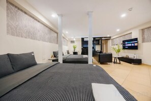 A modern hotel room with a large bed, a flat-screen TV, a desk, and a seating area. - VietHOME - 22 Pho Hue - Apartment 202 (Hanoi)